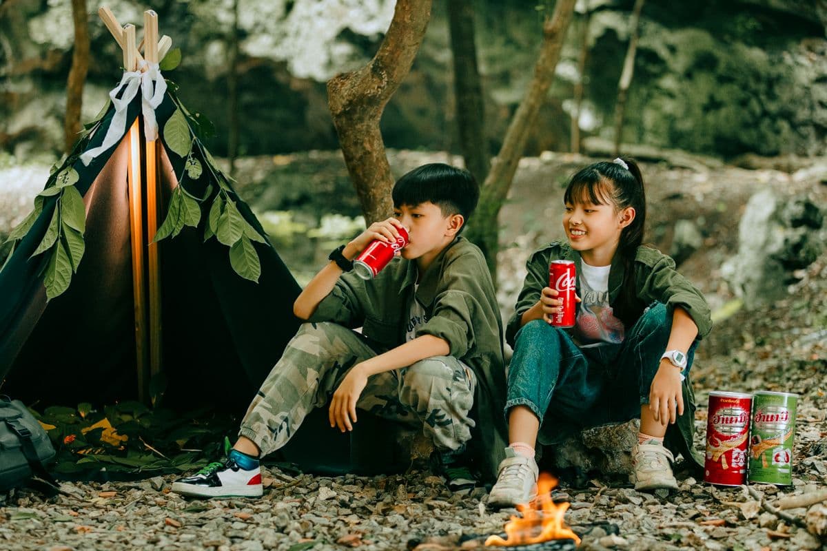 Children camping and having fun by a tent in the forest