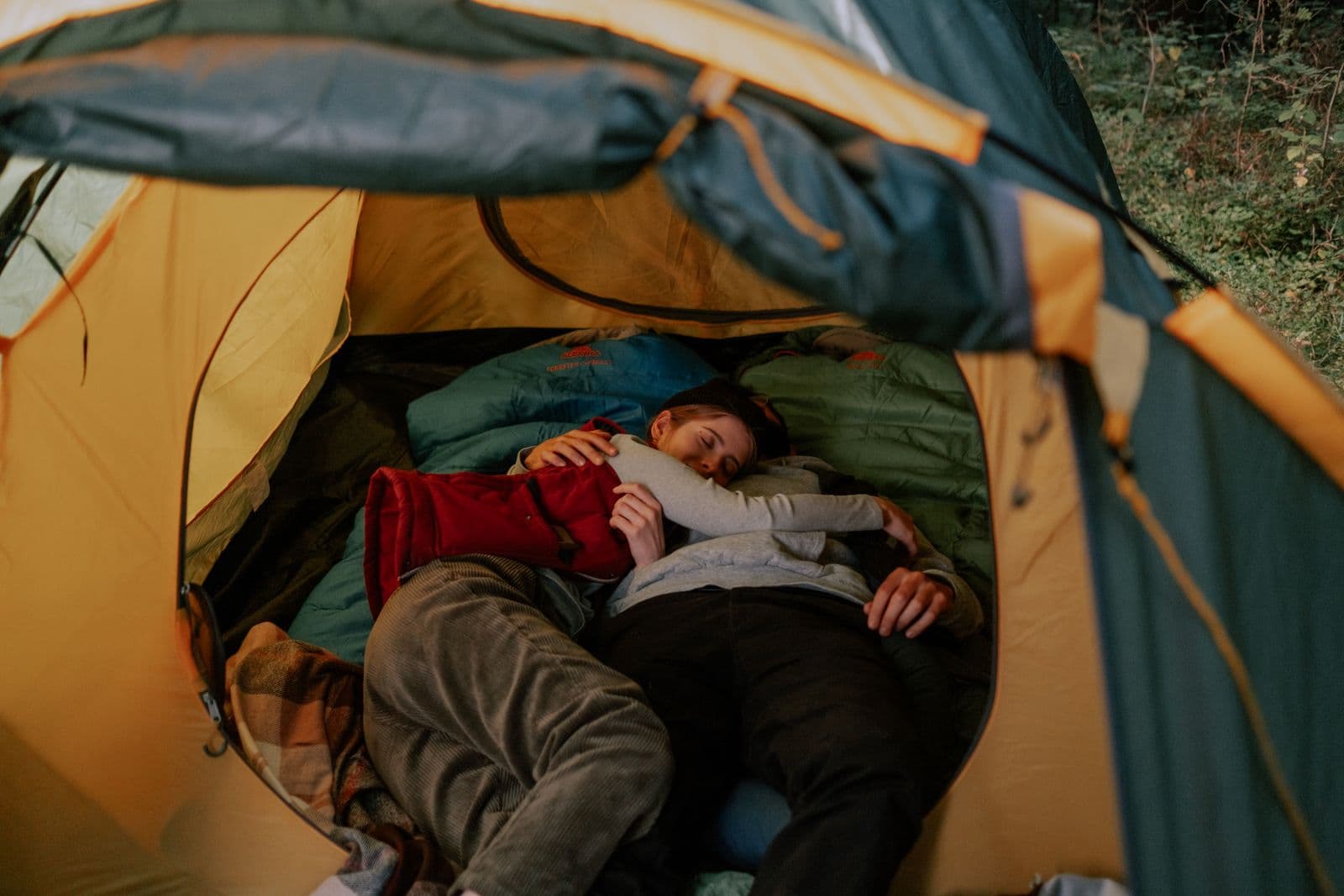 A couple resting in sleeping bags inside a tent