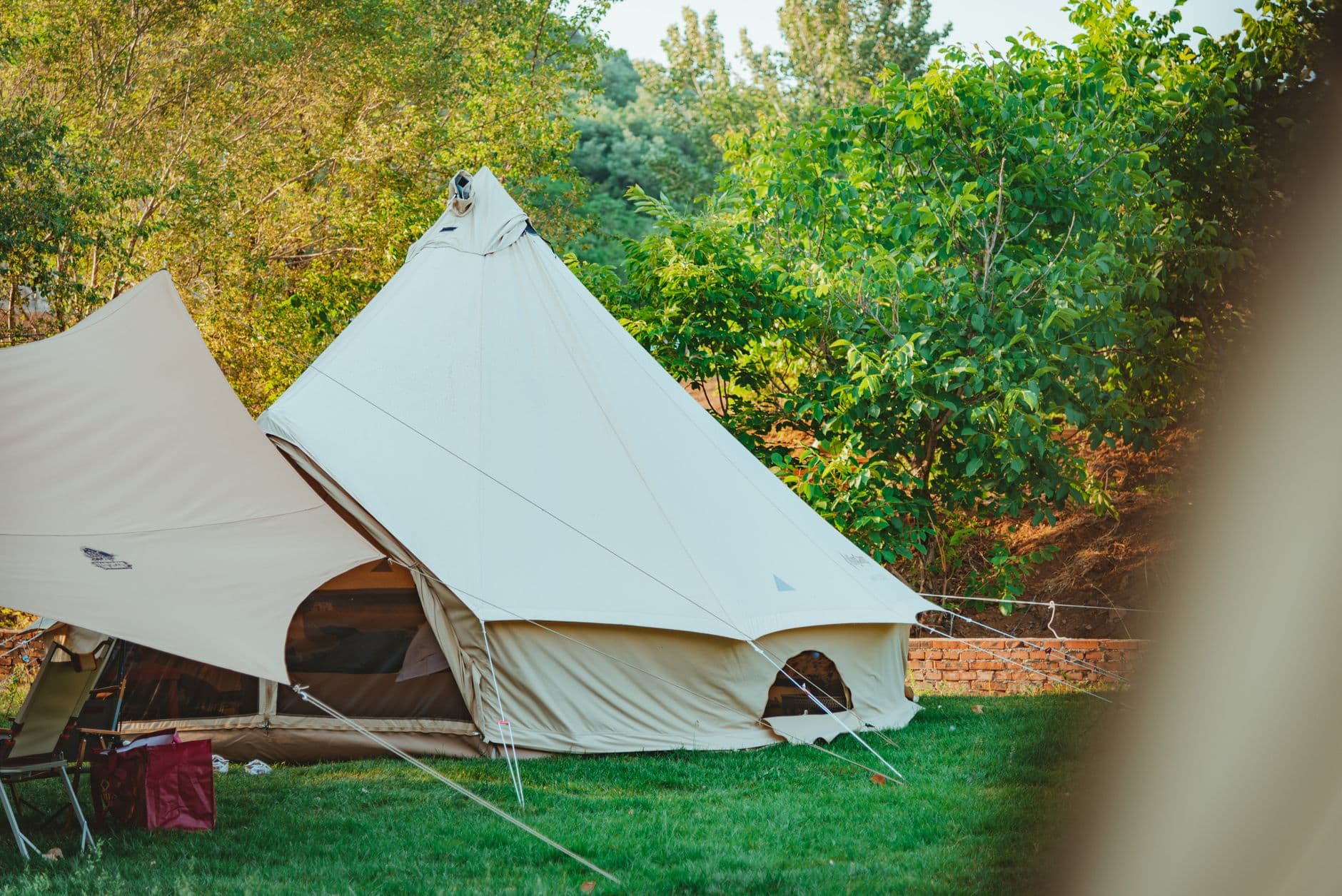 A canvas bell tent with its single center pole, pitched on grass