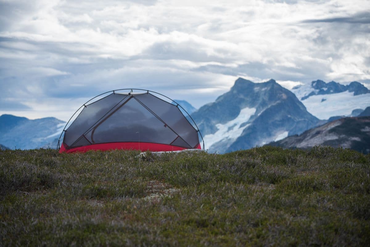 A camping tent pitched in front of a mountain landscape