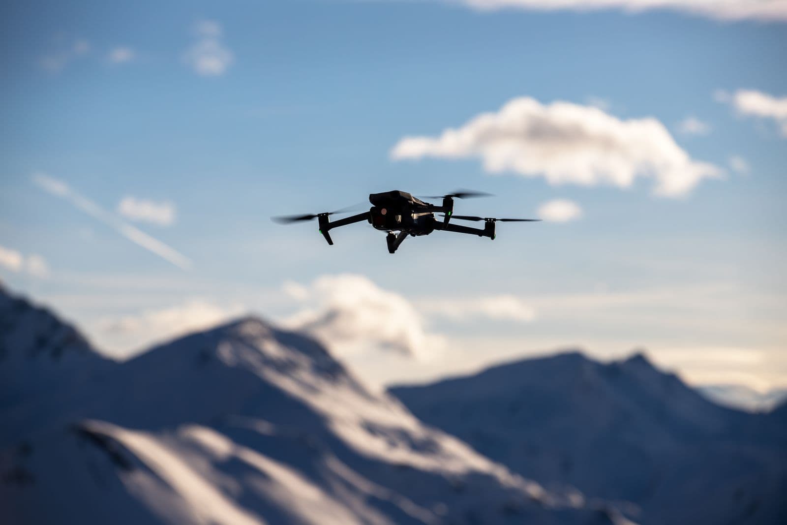 A drone flying over scenic snow-covered mountain peaks under a clear sky