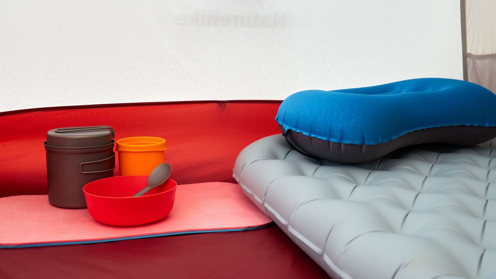 Inside a tent with an inflatable pillow, cookware, and sleeping gear