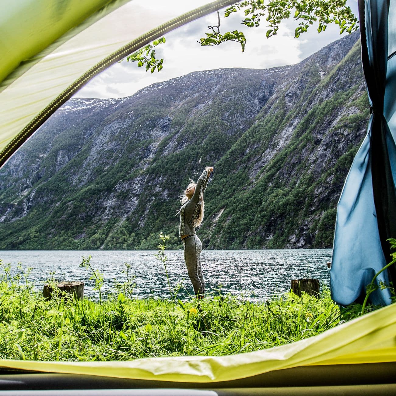 A camper stretching at a tent with a scenic view