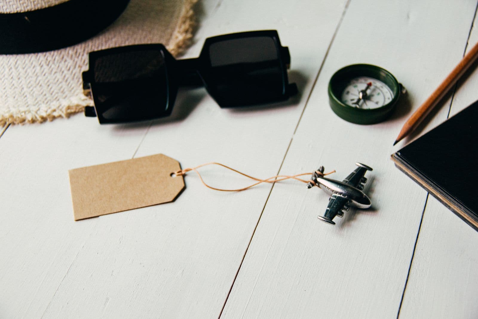 A flat lay of travel essentials — a model airplane, sunglasses, and a passport