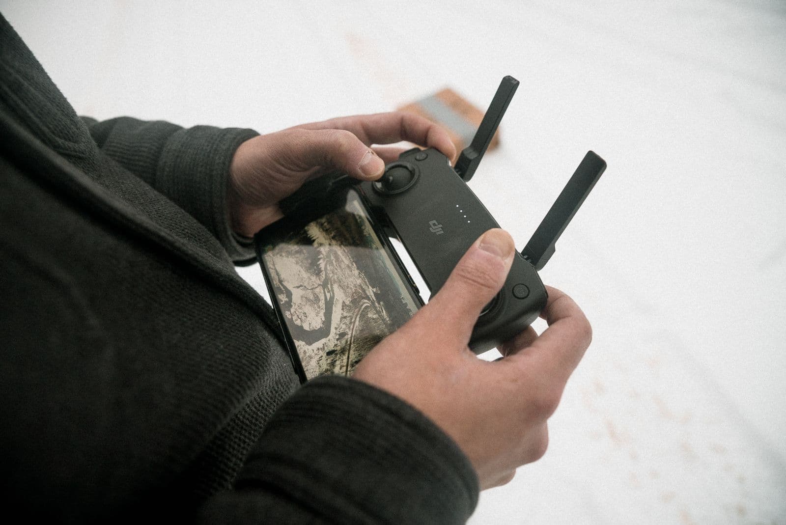 Close-up of hands operating a drone controller with a smartphone attached
