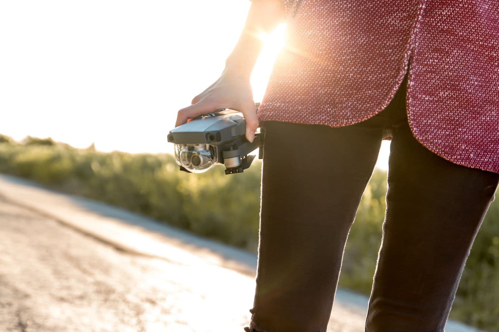 A person holding a drone on a sunny open road