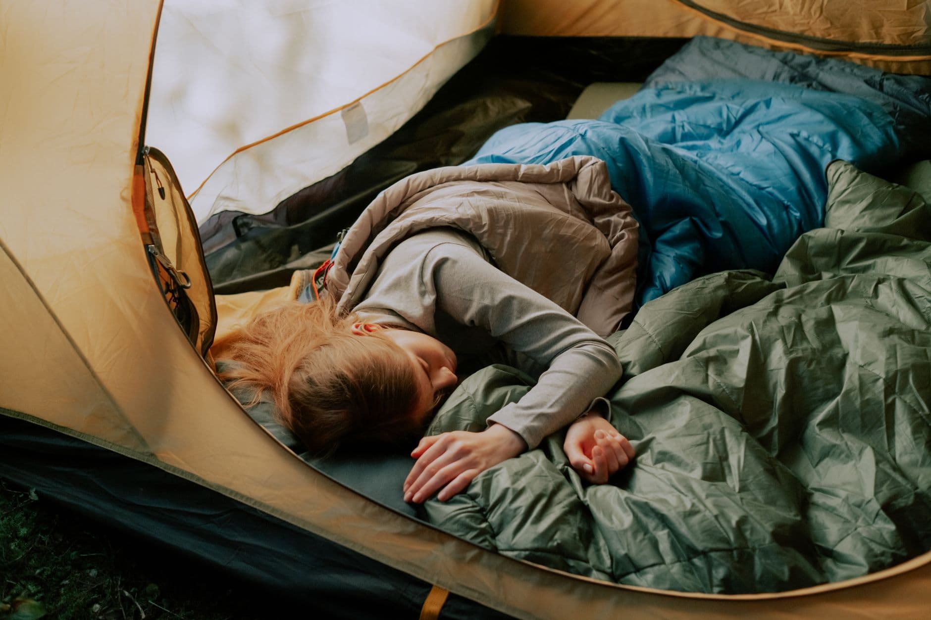 A camper sleeping comfortably in a tent