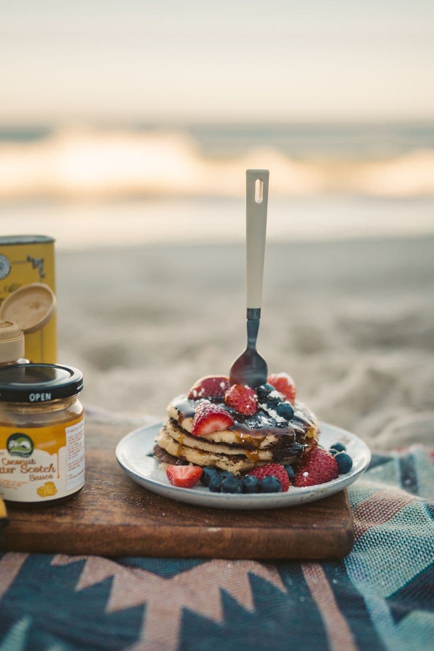 A plate of pancakes topped with berries at an outdoor campsite breakfast