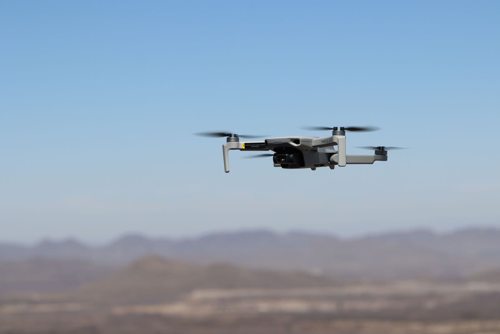 A drone flying over a desert landscape under a clear blue sky